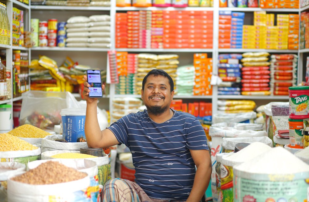 Tendero mostrando su teléfono O móvil en la mano