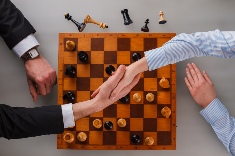 empresarios se dan la mano sobre el tablero de ajedrez